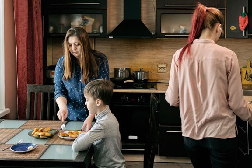 woman in plus-size shirt standing at table and putting nuggets into sons plate while serving table f...