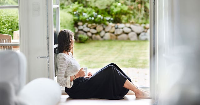 woman sitting in windowframe looking out