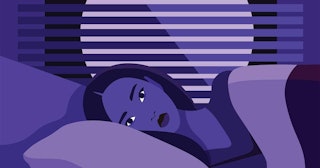 Woman lies in bed with open eyes in the dark room.