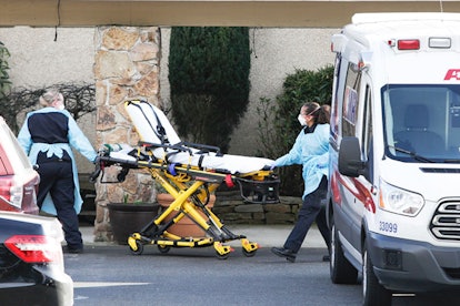A stretcher is moved from an AMR ambulance to the Life Care Center of Kirkland where one associate a...