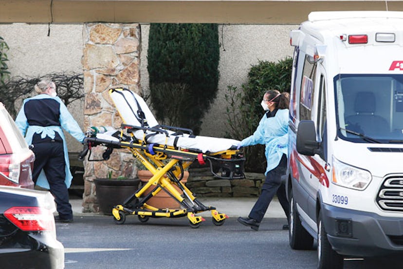 A stretcher is moved from an AMR ambulance to the Life Care Center of Kirkland where one associate a...