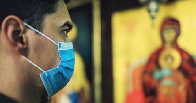 Portrait of young man wearing protective mask, in church.