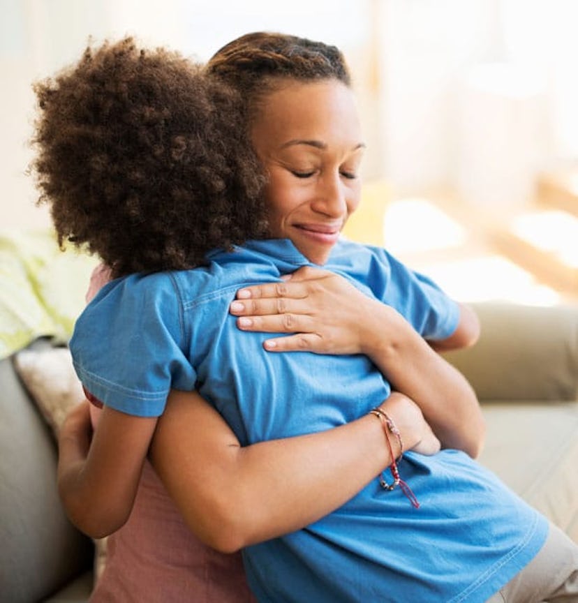 Mother and son hugging on sofa in living room