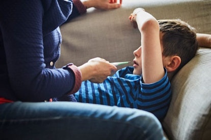 Mother taking sons temperature with digital thermomete