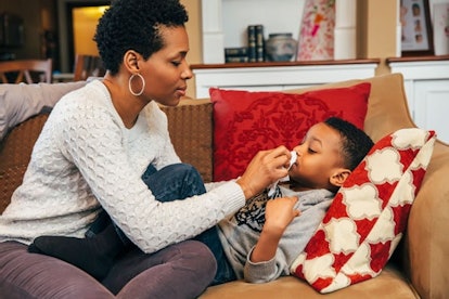 woman wiping nose of son on sofa