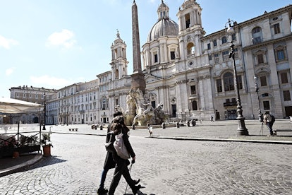 People walk across a deserted Piazza Navona in central Rome on March 12, 2020, as Italy shut all sto...