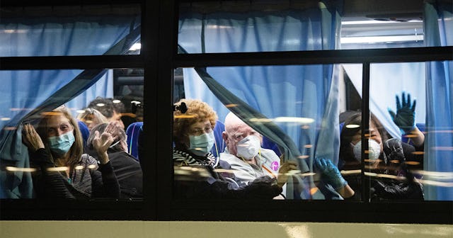 American citizens wave from a bus as they leave the quarantined Diamond Princess cruise ship