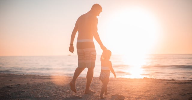 Foster care adoption, man holding child's hand at the beach at sunset