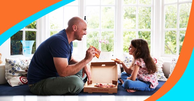 Dad and daughter sit on window seat at home sharing a pizza