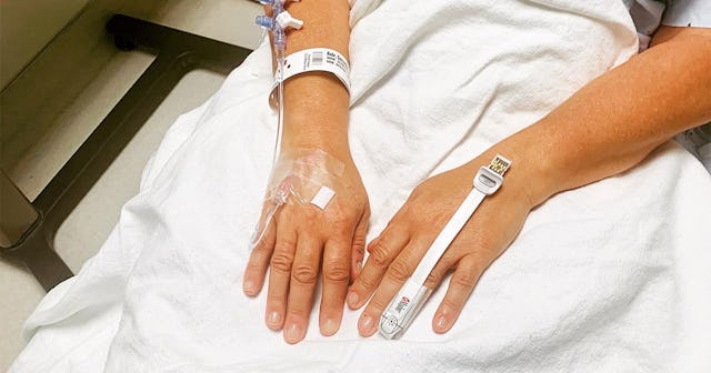 A close-up of Sam Kuhr's hands with infusion units while lying in a hospital bed