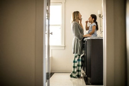 Mother and daughter brushing teeth in bathroom