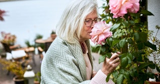 Senior woman smelling at rose in garden
