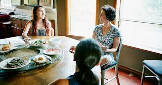 Daughters in discussion with mother at table