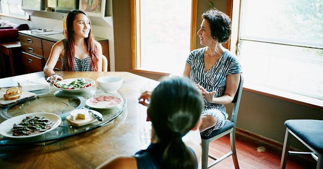 Daughters in discussion with mother at table