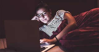 Woman lying in bed at home using laptop