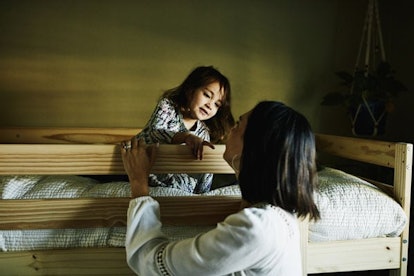 Young girl in discussion with mother while sitting on top bunk in bedroom