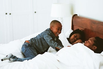 Young boy waking his parents and his father opens his eyes