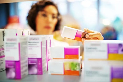 Female pharmacist checking medicines on rack