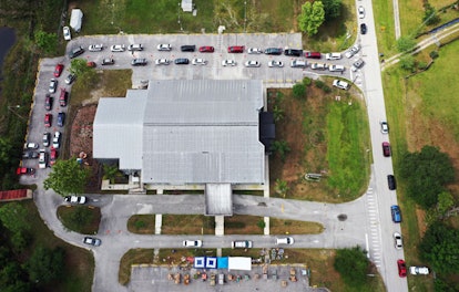 In this aerial view, a double line of cars is seen as people wait to receive food assistance from th...