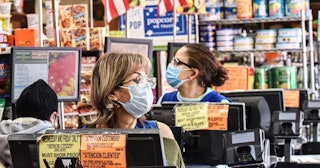 Cashiers wearing protective masks work in a grocery store in the Bushwick neighborhood of Brooklyn