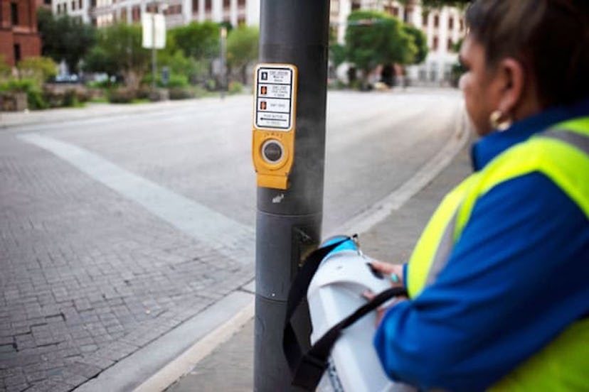 A San Antonio employee uses a disinfectant spray to mist a cross walk button