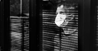 Man with mask looking out of window