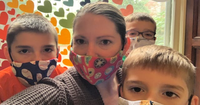 Mother and her three sons wearing protective masks for COVID-19 with different designs while taking ...