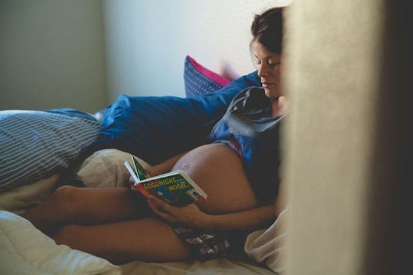 pregnant woman reading book in bed