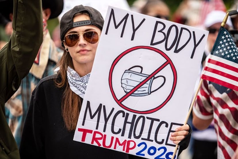 A protester holds up a sign protesting wearing a mask at the Texas State Capital building on April 1...