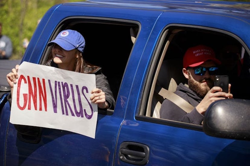 A woman holds a placard that seems to be calling the news network CNN a virus during the protest. Pr...