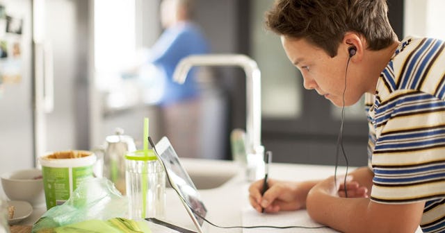 Young student working on digital tablet in his kitchen during lockdown