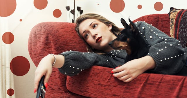 woman watching TV at home with her dog lying on sofa