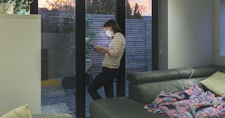 Woman in self isolation using smartphone by window