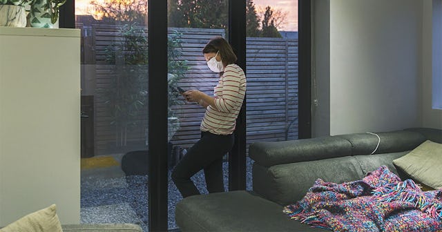Woman in self isolation using smartphone by window