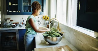 Woman washing organic kale in kitchen sink