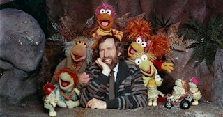 American puppeteer and filmmaker Jim Henson (1936 - 1990) with some of the Muppet cast from the chil...