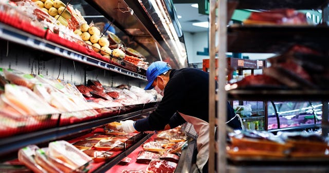 Wearing a mask, an employee stocks the meat section