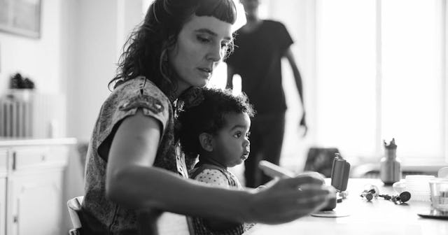 Woman working while sitting with daughter at table in house