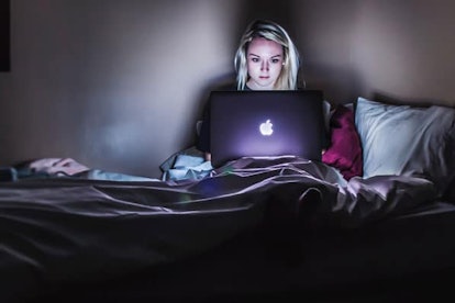 Woman working while sitting in bed in house