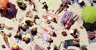 Crowd of people sunbathing on beach, over head view