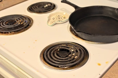 A white dirty stove with a pan on it