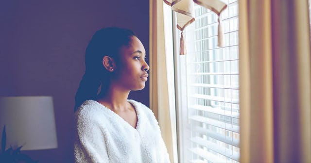 Woman Looking Through Window At Home