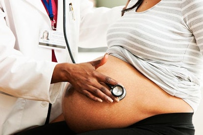 Female doctor checking pregnant woman's belly
