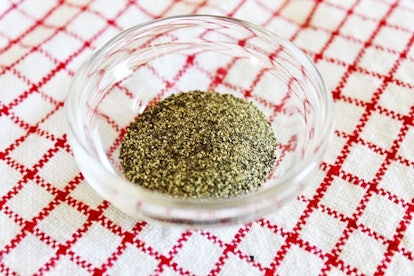 A see-through bowl of ground pepper placed on a checkered tablecloth