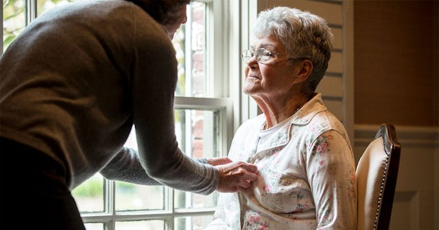 Woman buttoning pajamas of mother near window