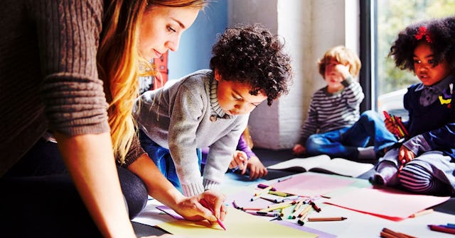 Teacher drawing with students on floor at preschool