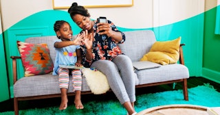 mother and daughter taking selfie in living room