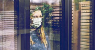 Teenage girl looking through window with mask