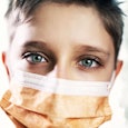 Little boy wearing anti virus mask staying at home
