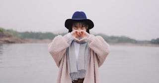 Woman wearing hat meaning a heart with her hands